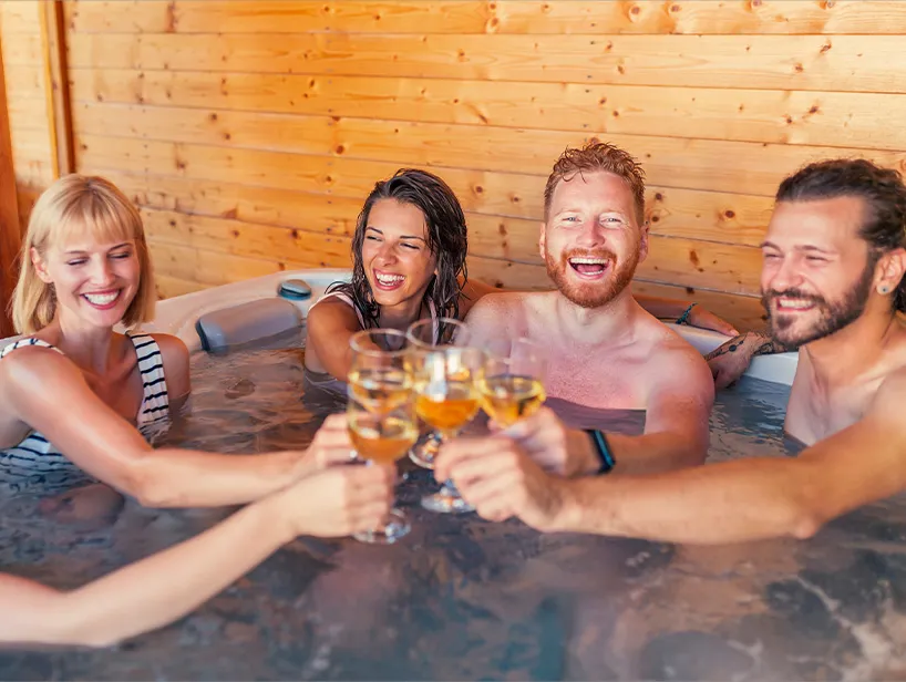 Freunde stoßen mit Getränken im Whirlpool an – ausgelassene Stimmung für einen gelungenen Abend am Whirlpool.