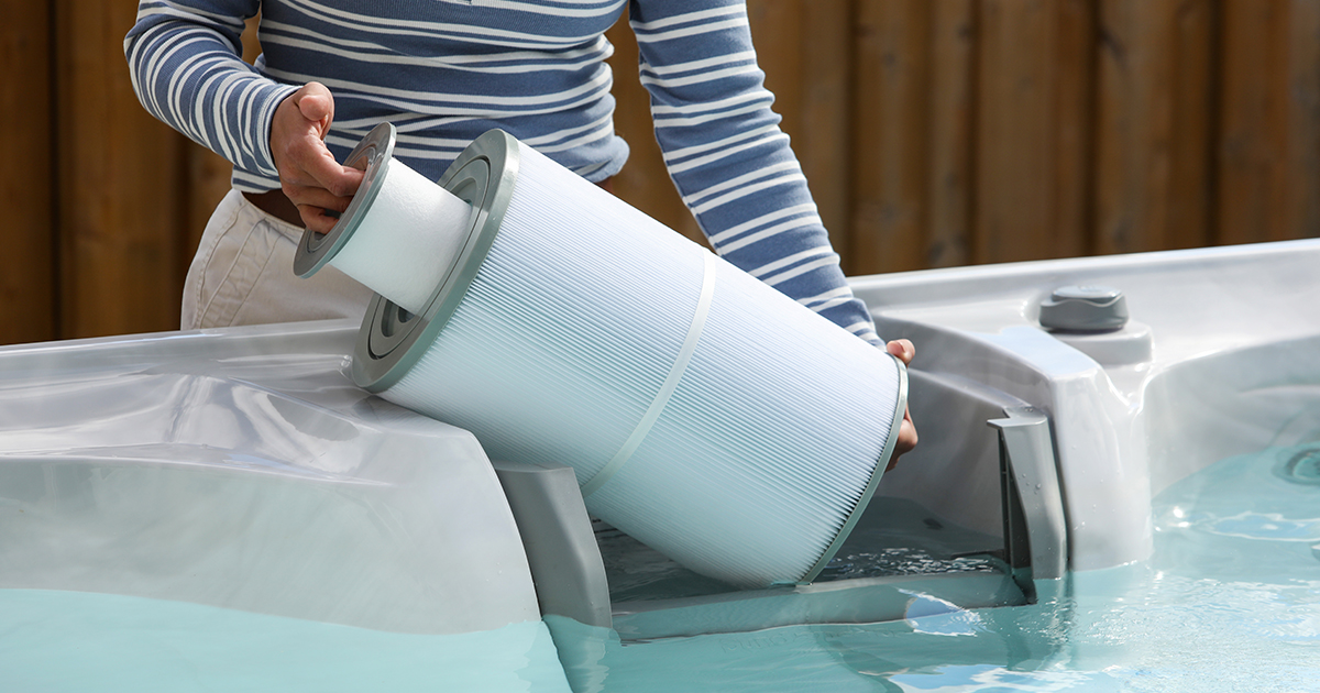 Person reinigt Whirlpool-Filter und setzt Filterkartusche ins Wasser zur Wartung ein