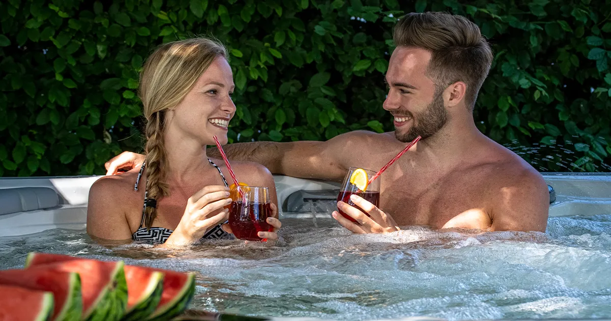 Paar entspannt gemeinsam im Whirlpool mit Getränken und sprudelndem Wasser im Garten
