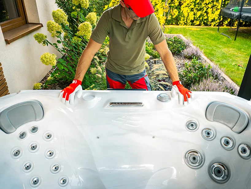 Mann mit Schutzhandschuhen prüft die Position eines Whirlpools im Garten – Detailansicht der Sitzplätze und Massagedüsen.