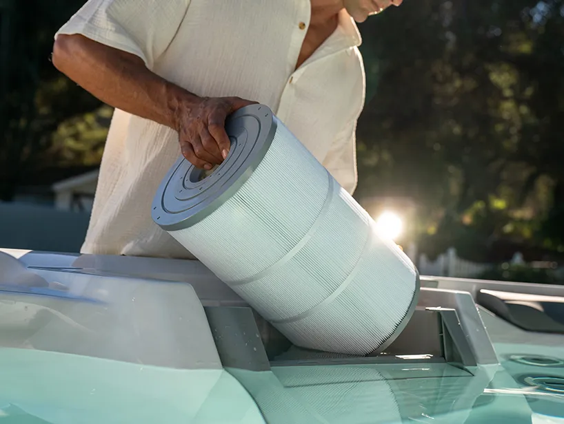 Mann entnimmt Whirlpool-Filter zur Reinigung – effektive Wasserpflege beginnt beim Whirlpool reinigen.